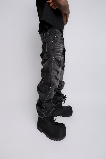 Person wearing black distressed cargo pants and black boots on a light gray background