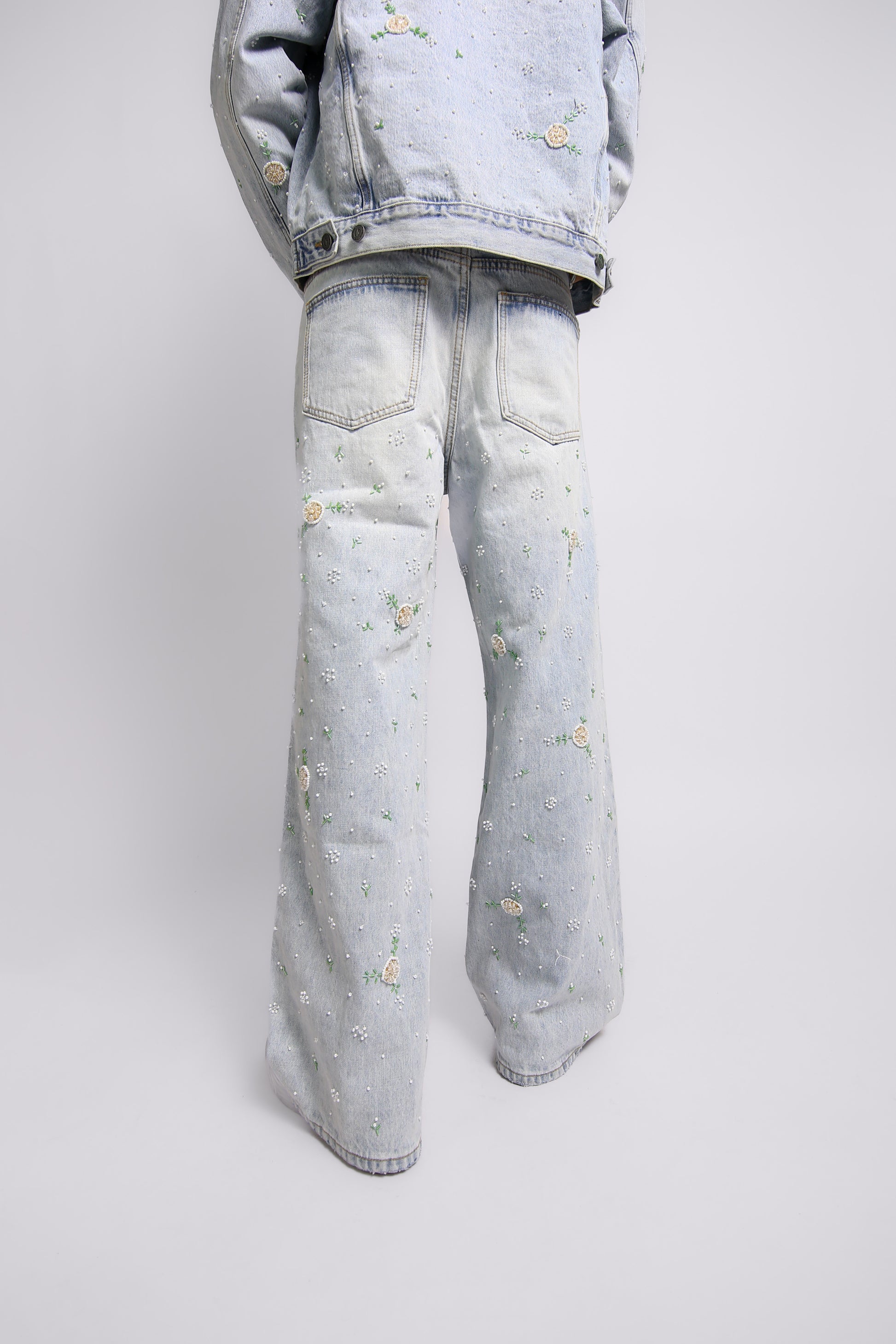 Light blue denim jacket and jeans with floral embroidery on a white background