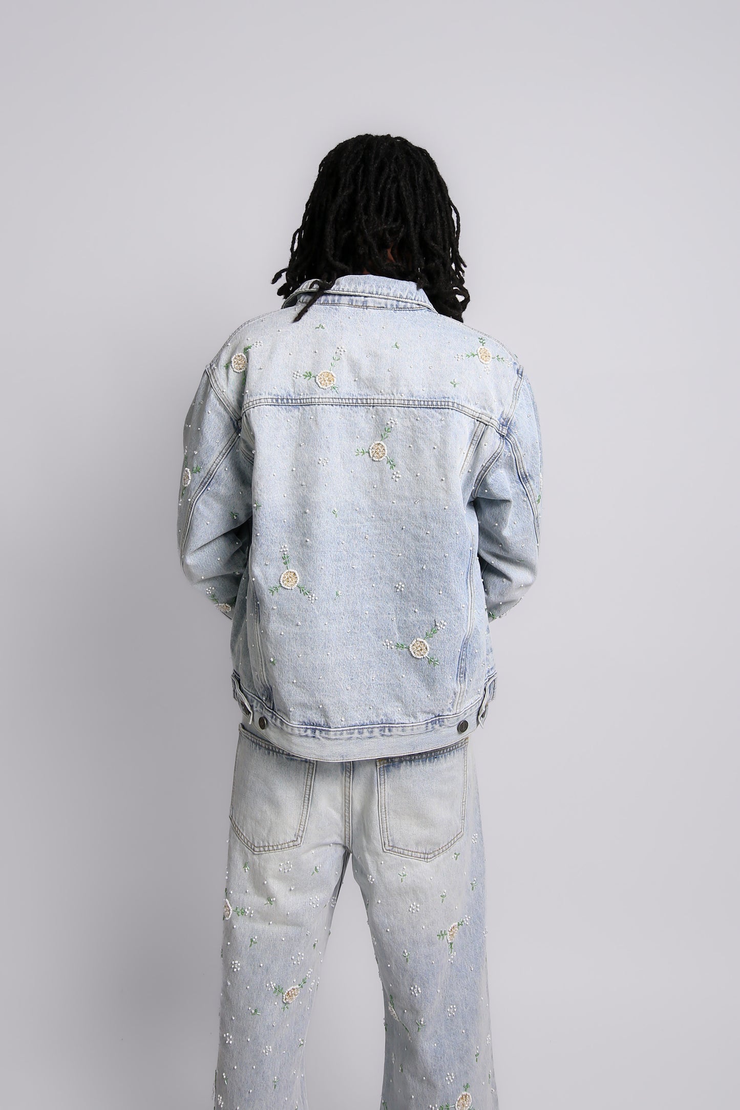 Person wearing a light blue denim jacket and pants on a white background