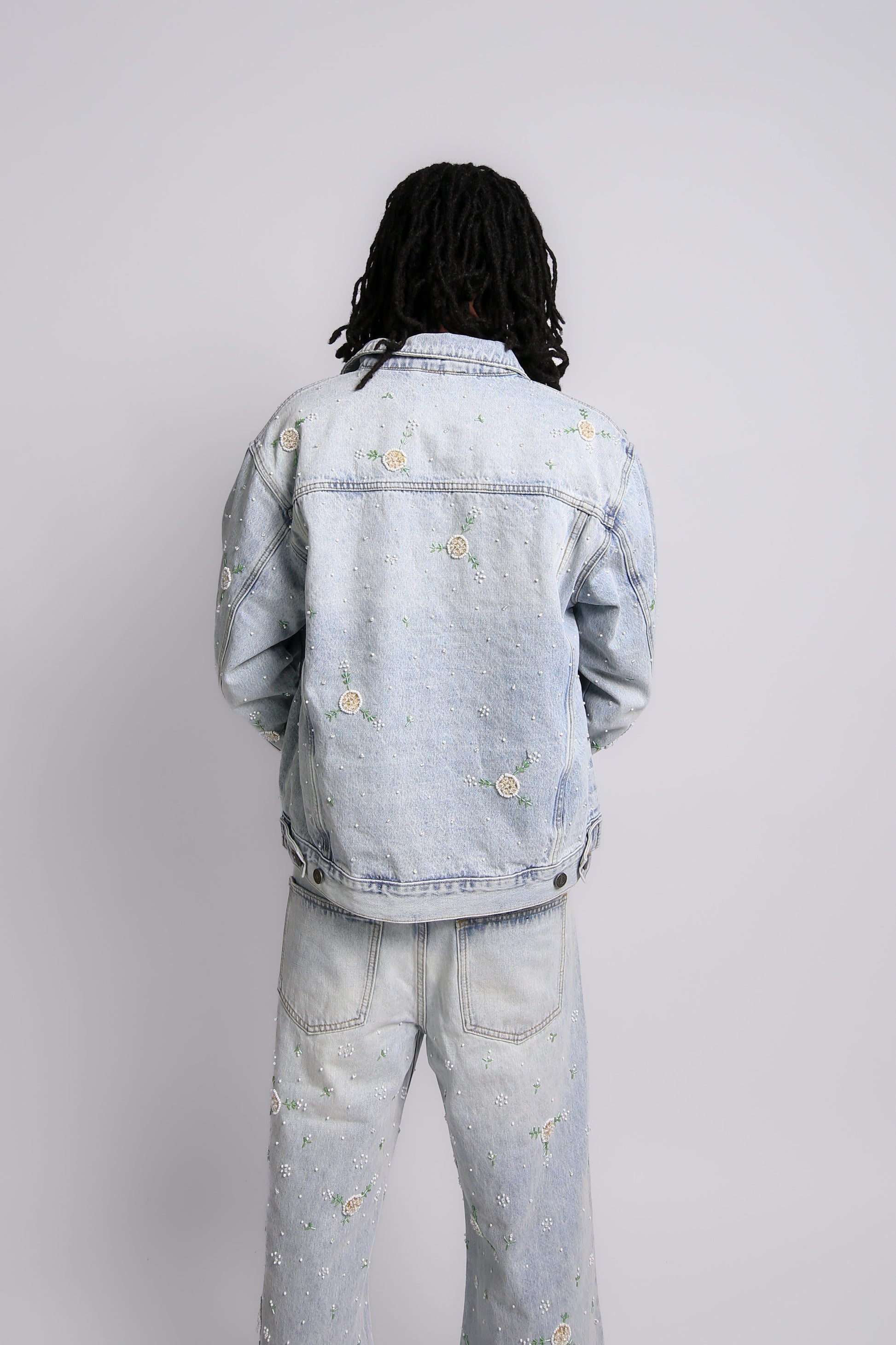 Person wearing a light blue denim jacket and pants on a white background