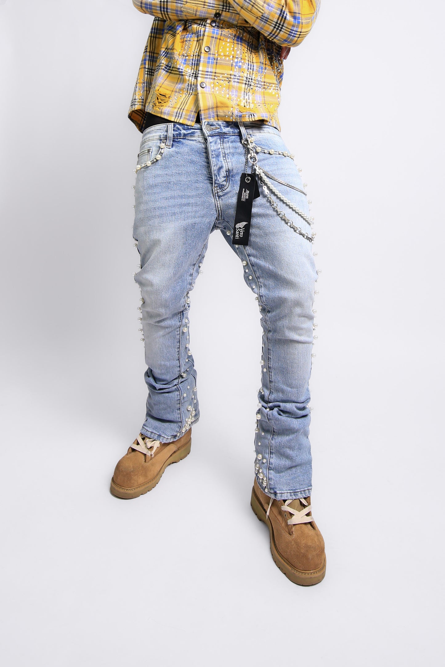 Person wearing light blue distressed jeans with a yellow plaid shirt on a white background